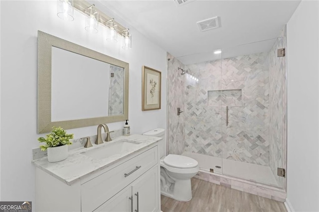bathroom with a shower stall, wood finished floors, toilet, and vanity