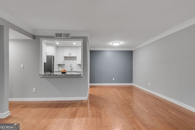 1015 Dunbar Dr, Dunwoody, GA 30338 - kitchen featuring freestanding refrigerator, a breakfast bar area, wood finished floors, crown molding, and white cabinetry