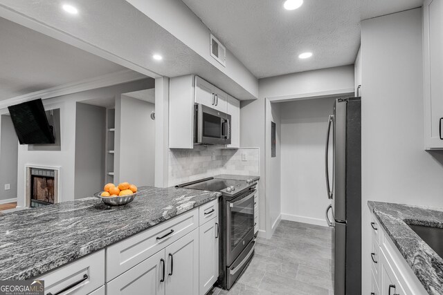 1015 Dunbar Dr, Dunwoody, GA 30338 - kitchen featuring stainless steel microwave, electric range, white cabinets, tasteful backsplash, and ceiling fan