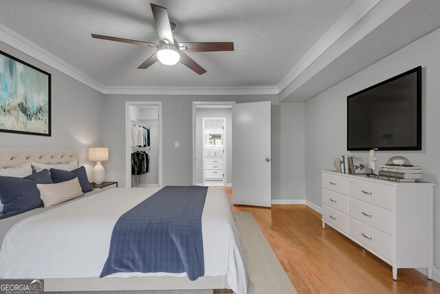 1015 Dunbar Dr, Dunwoody, GA 30338 - unfurnished bedroom with a spacious closet, light wood finished floors, a textured ceiling, crown molding, and baseboards