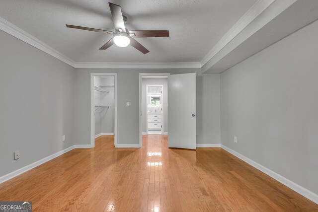 1015 Dunbar Dr, Dunwoody, GA 30338 - bedroom with light wood finished floors, crown molding, baseboards, ceiling fan, and a walk in closet