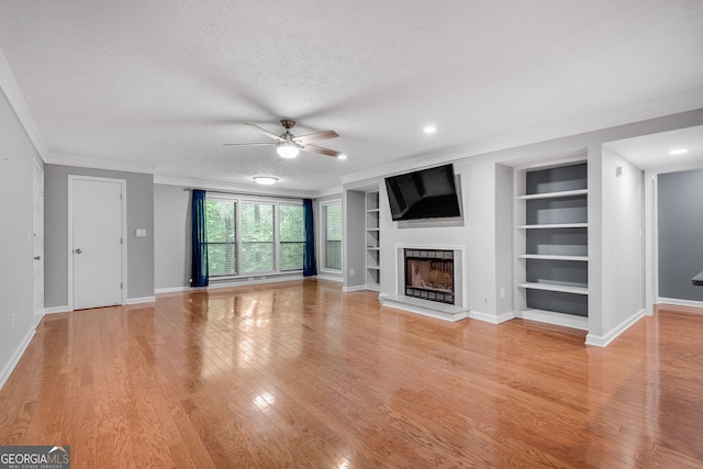 1015 Dunbar Dr, Dunwoody, GA 30338 - unfurnished living room featuring a ceiling fan, ornamental molding, built in features, a fireplace with raised hearth, and light wood finished floors