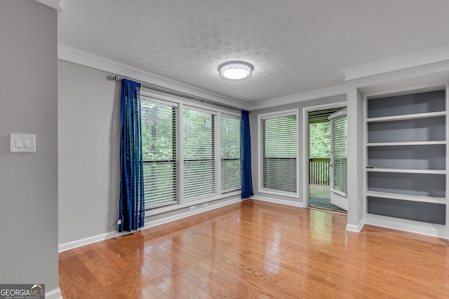 1015 Dunbar Dr, Dunwoody, GA 30338 - unfurnished living room featuring built in features, ornamental molding, light wood-style flooring, baseboards, and a textured ceiling