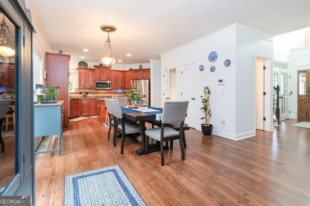 dining space with wood finished floors, ornamental molding, baseboards, and recessed lighting