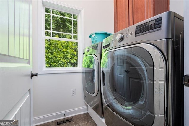 clothes washing area featuring independent washer and dryer, cabinet space, baseboards, and healthy amount of natural light