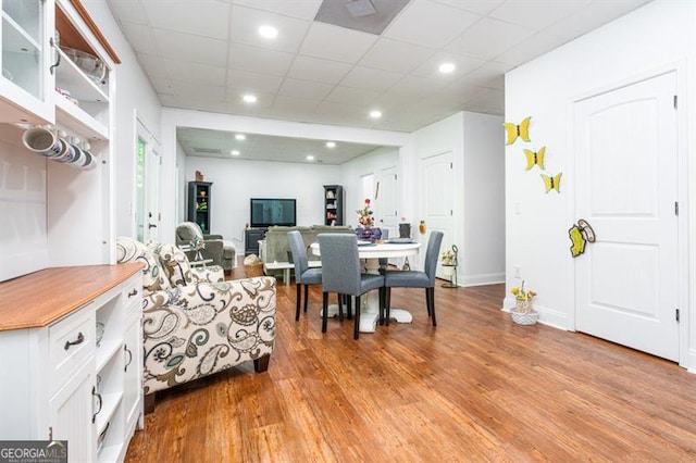 living room with light wood-type flooring, a paneled ceiling, baseboards, and recessed lighting