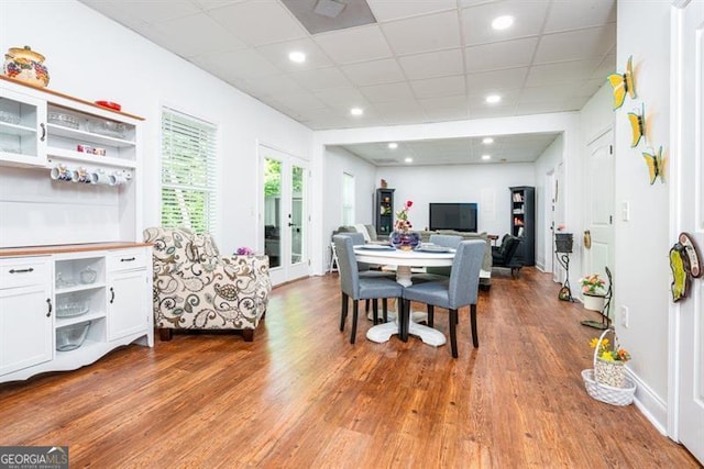 dining area with wood finished floors, a paneled ceiling, recessed lighting, and french doors