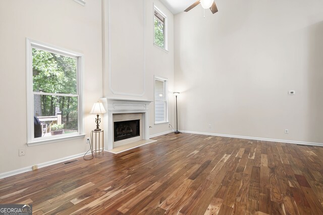 5034 Kingsbridge Pass, Powder Springs, GA 30127 - unfurnished living room featuring a ceiling fan, hardwood / wood-style floors, a towering ceiling, a high end fireplace, and baseboards