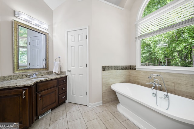 5034 Kingsbridge Pass, Powder Springs, GA 30127 - bathroom featuring vanity, a freestanding tub, lofted ceiling, tile patterned flooring, and baseboards