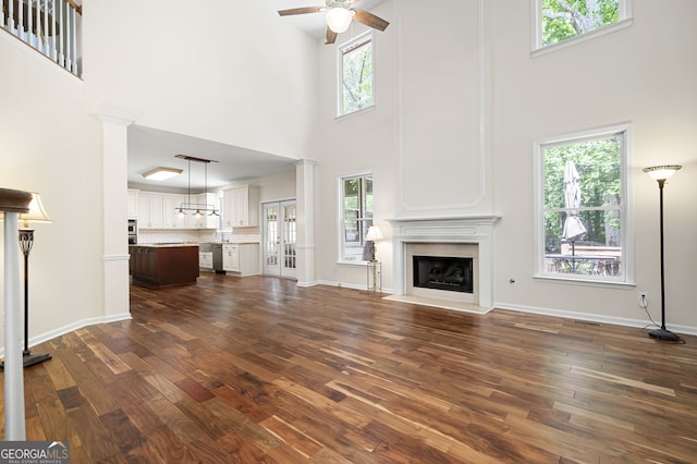 5034 Kingsbridge Pass, Powder Springs, GA 30127 - unfurnished living room featuring a high ceiling, dark wood-style floors, ceiling fan, a fireplace, and baseboards