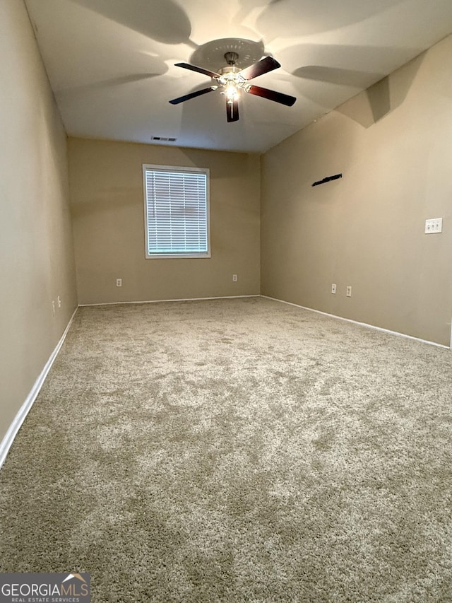 spare room with ceiling fan, carpet, and baseboards