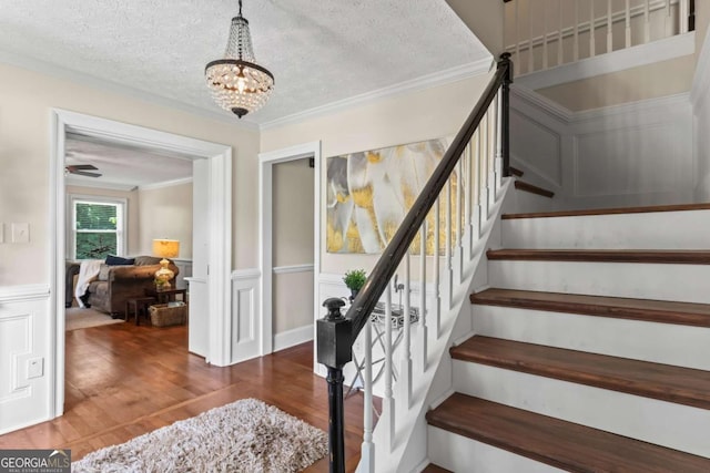 3441 Sherrod Dr SW, Marietta, GA 30060 - stairway with wood finished floors, a textured ceiling, crown molding, a chandelier, and wainscoting