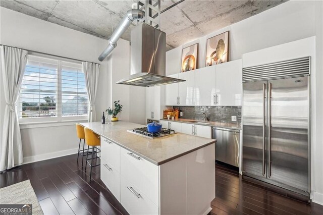206 NE 11th St NE Unit Ph703, Atlanta, GA 30309 - kitchen with appliances with stainless steel finishes, island range hood, dark wood-type flooring, and backsplash