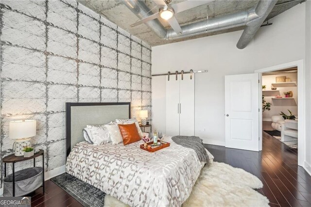 206 NE 11th St NE Unit Ph703, Atlanta, GA 30309 - bedroom featuring a barn door, wood finished floors, baseboards, a high ceiling, and ceiling fan