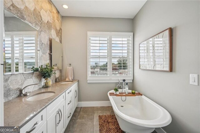 206 NE 11th St NE Unit Ph703, Atlanta, GA 30309 - bathroom featuring a soaking tub, double vanity, decorative backsplash, and baseboards
