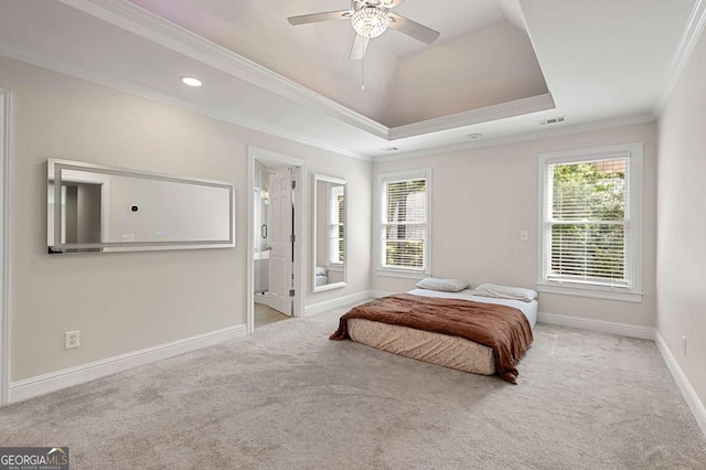 carpeted bedroom featuring baseboards, multiple windows, ornamental molding, a raised ceiling, and connected bathroom