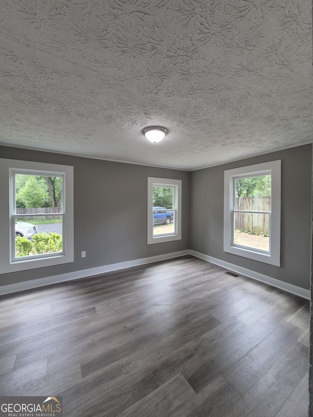 spare room featuring wood finished floors, baseboards, and a textured ceiling