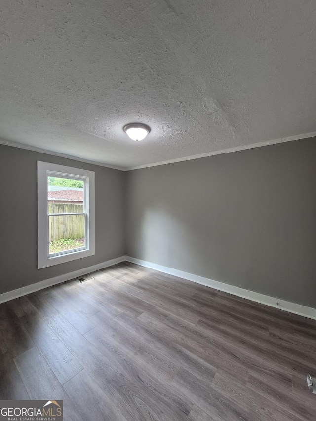 spare room featuring wood finished floors, ornamental molding, a textured ceiling, and baseboards