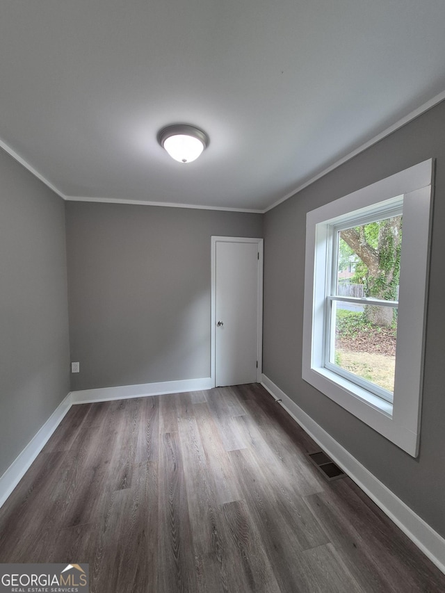 unfurnished room with dark wood-style floors, crown molding, and baseboards