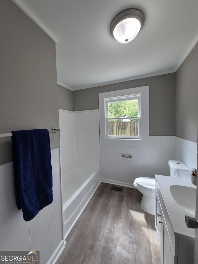 full bathroom featuring wood finished floors, toilet, vanity, a wainscoted wall, and ornamental molding