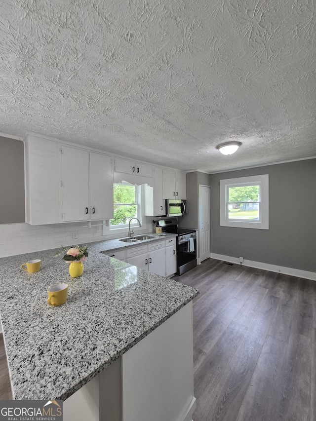 kitchen featuring appliances with stainless steel finishes, a sink, dark wood finished floors, a peninsula, and a textured ceiling