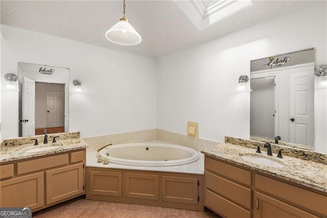bathroom featuring a skylight, a bath, two vanities, and tile patterned flooring