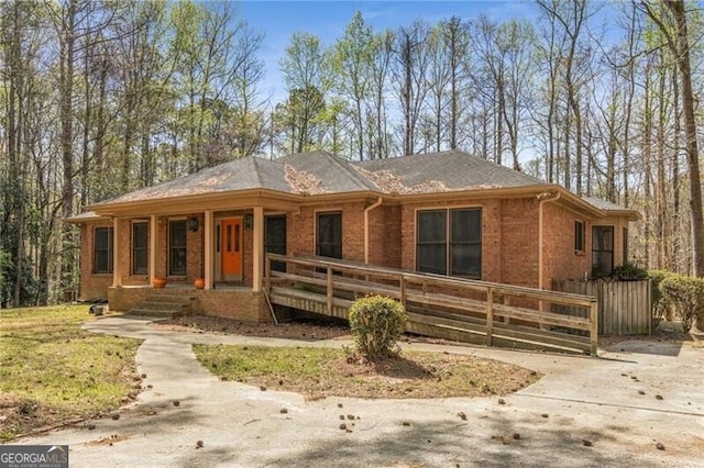view of front of home with a porch, brick siding, and fence
