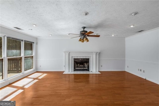 unfurnished living room with a ceiling fan, a textured ceiling, wood finished floors, ornamental molding, and baseboards