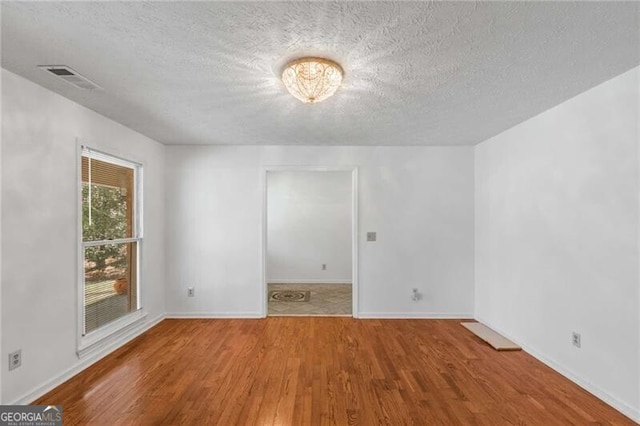 spare room with wood finished floors, a textured ceiling, and baseboards