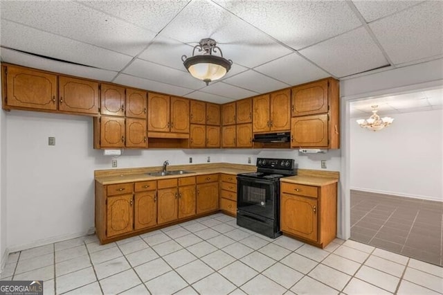 kitchen featuring black electric range oven, under cabinet range hood, a sink, brown cabinets, and a paneled ceiling