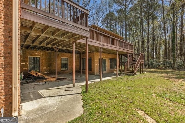 back of house featuring a yard, a patio area, stairway, a wooden deck, and brick siding