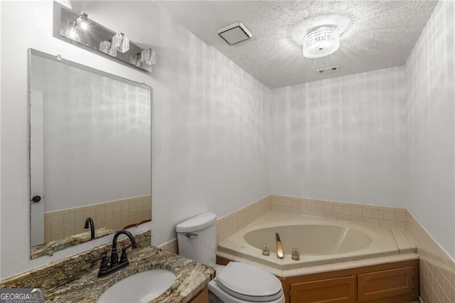 bathroom featuring a bath, toilet, a textured ceiling, and vanity
