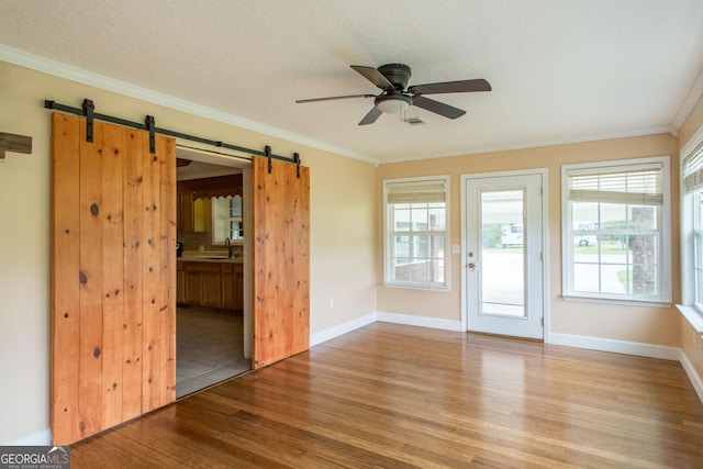 3842 Kay Cir, Blackshear, GA 31516 - empty room with a barn door, wood finished floors, a ceiling fan, ornamental molding, and plenty of natural light