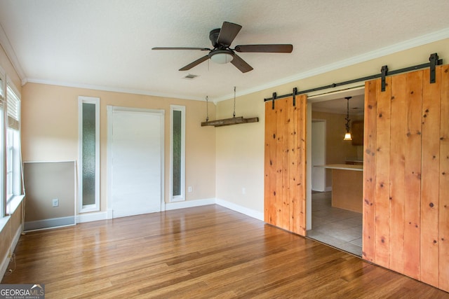 3842 Kay Cir, Blackshear, GA 31516 - unfurnished bedroom featuring a barn door, wood finished floors, ornamental molding, baseboards, and ceiling fan