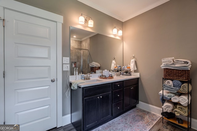 bathroom featuring wood finished floors, a shower stall, ornamental molding, baseboards, and double vanity