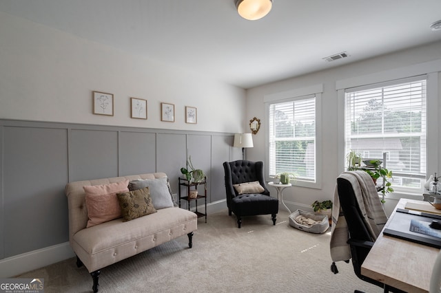 carpeted office space featuring a decorative wall and wainscoting