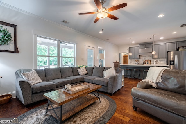 living area featuring crown molding, dark wood-type flooring, a ceiling fan, and recessed lighting