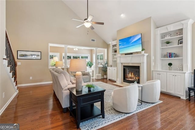 3365 Buffington Ln, Cumming, GA 30040 - living area featuring a ceiling fan, a glass covered fireplace, stairway, high vaulted ceiling, and wood finished floors