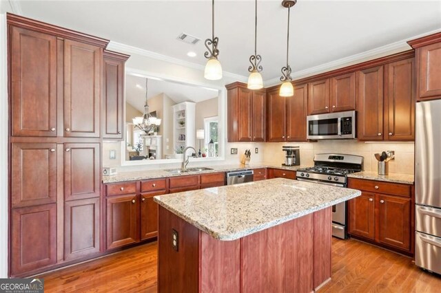 3365 Buffington Ln, Cumming, GA 30040 - kitchen with appliances with stainless steel finishes, a sink, a kitchen island, wood finished floors, and ornamental molding