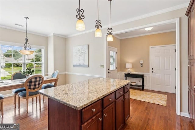 3365 Buffington Ln, Cumming, GA 30040 - kitchen with dark wood finished floors, pendant lighting, a center island, light stone counters, and ornamental molding