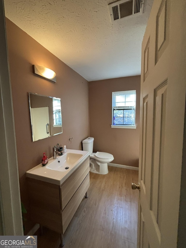 3709 Charlotte Dr, Rex, GA 30273 - half bath with wood finished floors, toilet, vanity, a textured ceiling, and baseboards