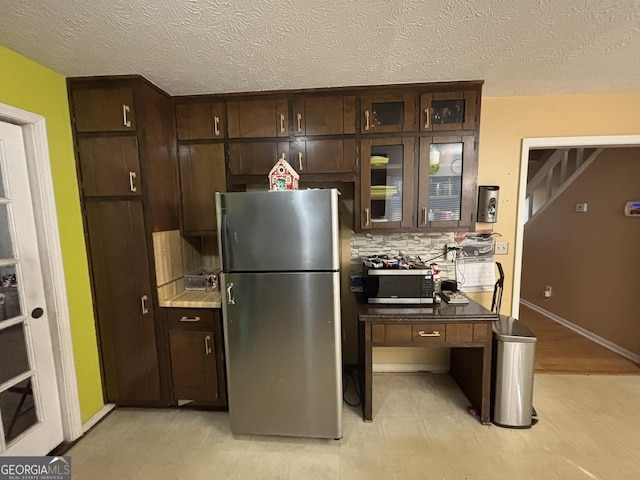 3709 Charlotte Dr, Rex, GA 30273 - kitchen featuring appliances with stainless steel finishes, dark brown cabinets, decorative backsplash, a textured ceiling, and glass insert cabinets