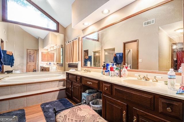 bathroom with lofted ceiling, a garden tub, healthy amount of natural light, and double vanity