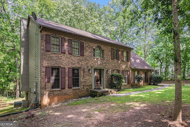 view of front of property with brick siding, a chimney, and central AC