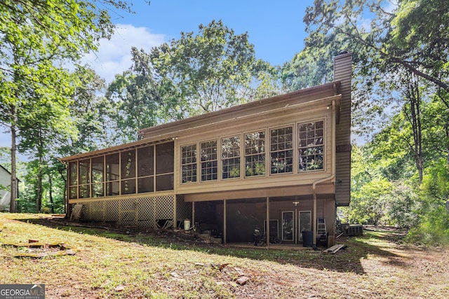 back of house featuring a sunroom and a chimney