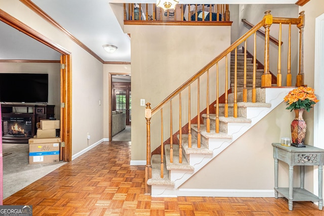 stairs with baseboards, a glass covered fireplace, and crown molding