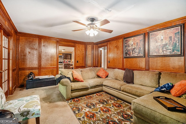 carpeted living area featuring ceiling fan and wood walls