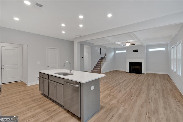 kitchen with a sink, dishwasher, a fireplace, a center island with sink, and light wood finished floors