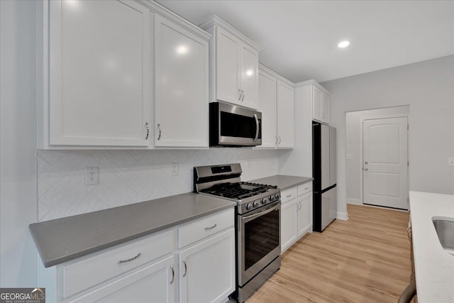 116 Daffodil Lndg, Dallas, GA 30132 - kitchen featuring stainless steel appliances, white cabinets, backsplash, light wood-style flooring, and baseboards
