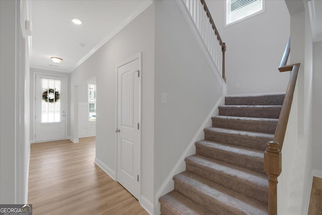 staircase featuring ornamental molding, baseboards, and wood finished floors